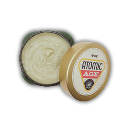 Face scrub in open green tin with Atomic Age branding and cream colored texture