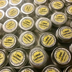 Lip balm tins with yellow labels and Herbs & Soil branding, metal containers