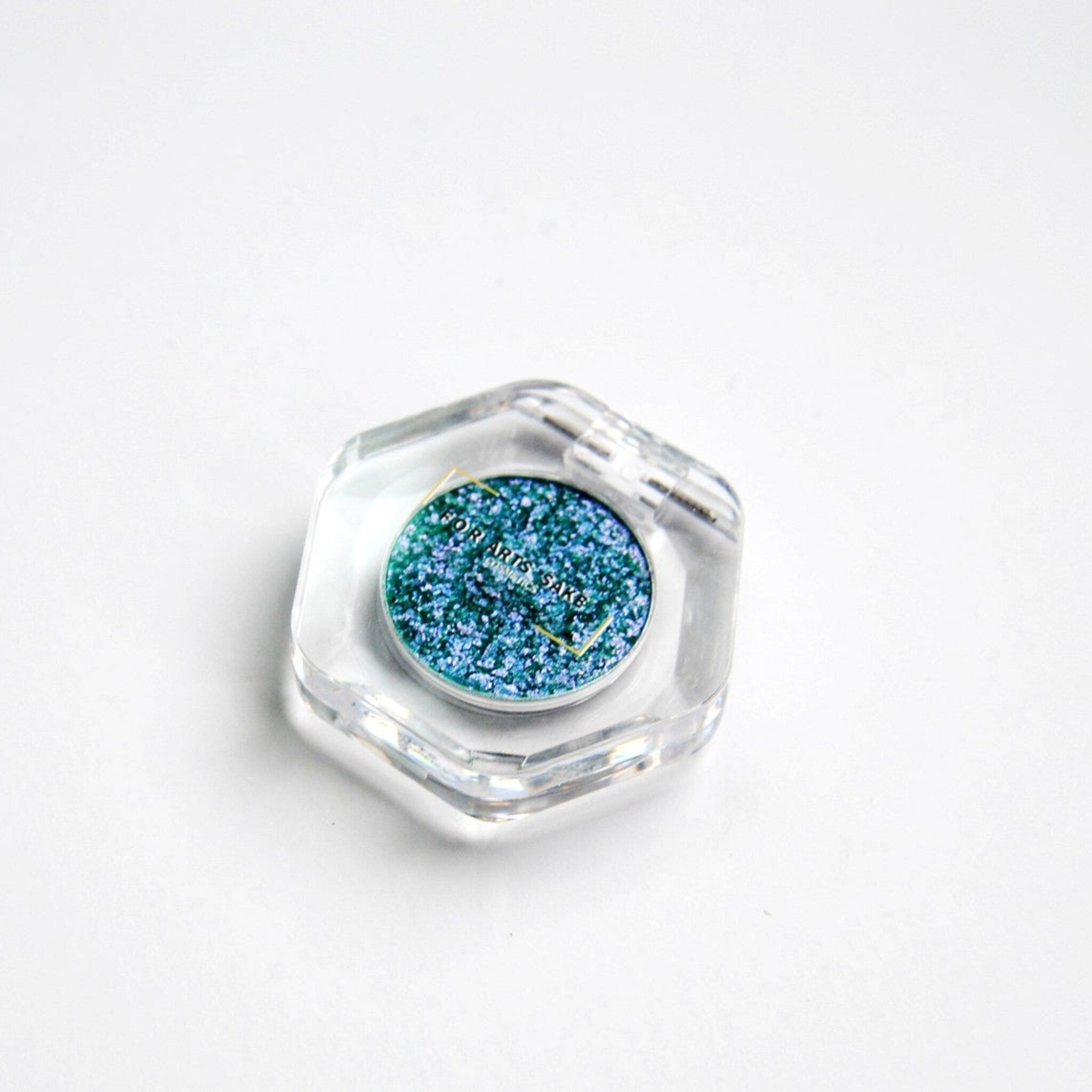 Close-up of teal, blue, and silver multichrome eyeshadow with iridescent chromashift effect on fingertip