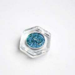 Close-up of teal, blue, and silver multichrome eyeshadow with iridescent chromashift effect on fingertip