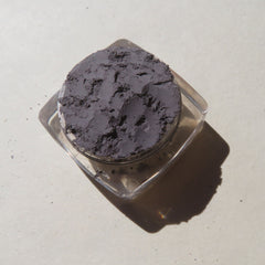 Side view of matte medium gray mica mineral eyeshadow in loose powder form with vegan label visible