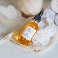 Oil cleanser bottle with amber liquid, black dropper, and Aligned Apothecary label on white pads