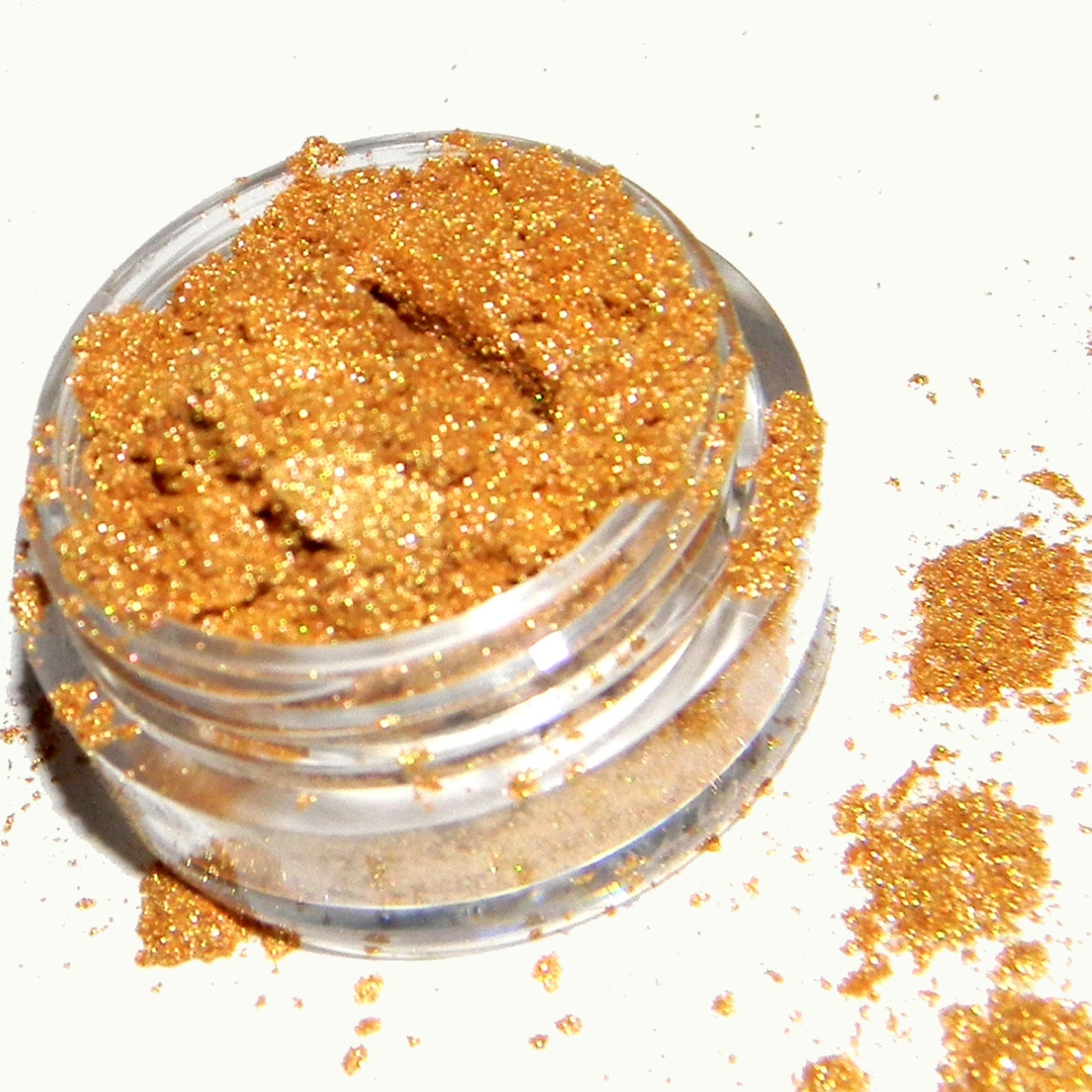 Close-up of shimmery gold eyeshadow pan with reflective metallic finish for festive looks