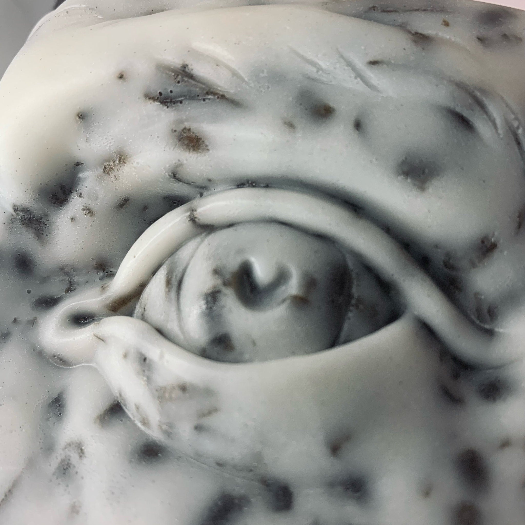 Abstract sculpture with white and gray tones, speckled pattern, curved lines, and eye-like shape
