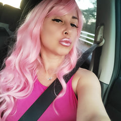 Pink wig with long wavy hair, worn by a person in a car, with pink top and seatbelt on