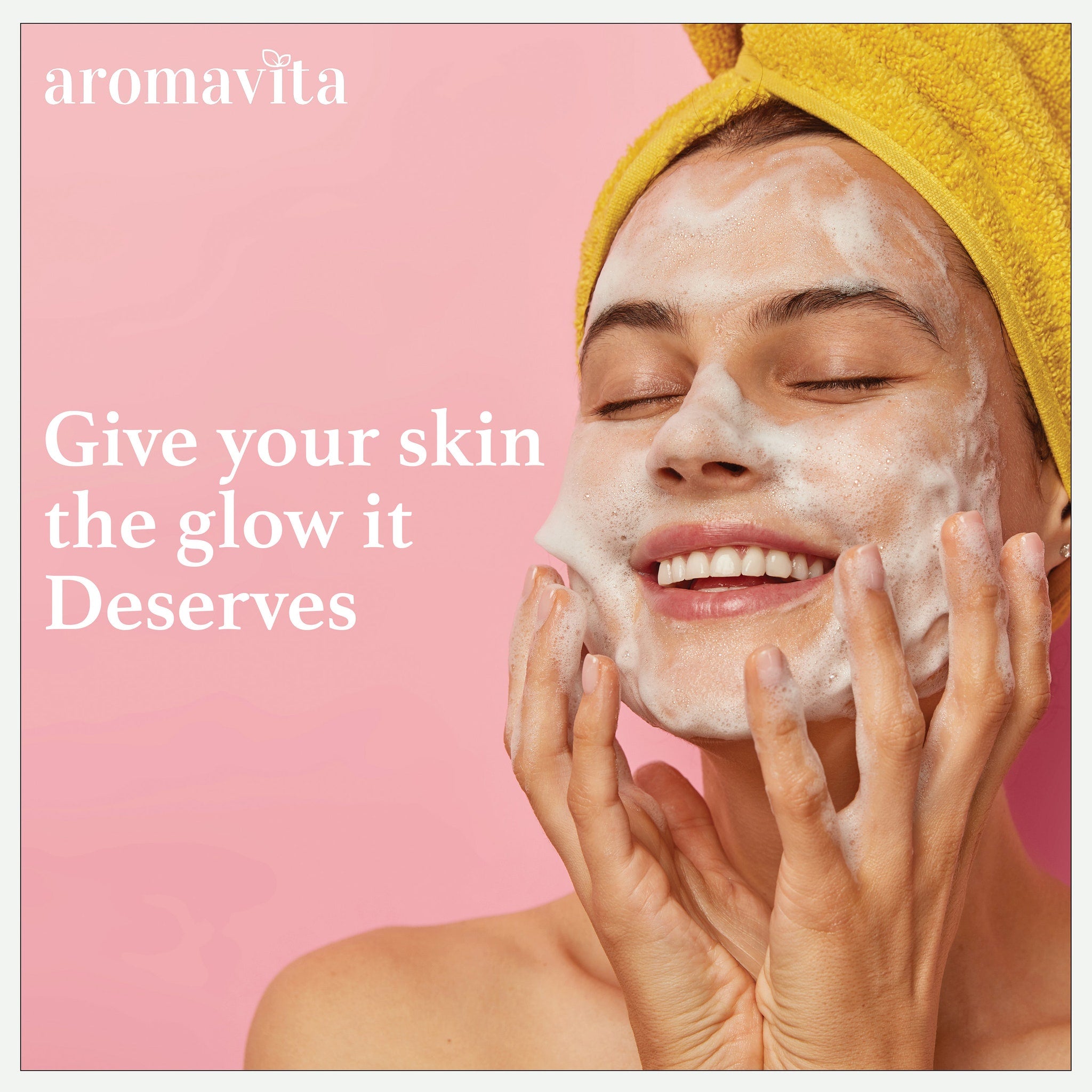 Facial cleanser with white foam, yellow towel, and pink background, aromavita brand