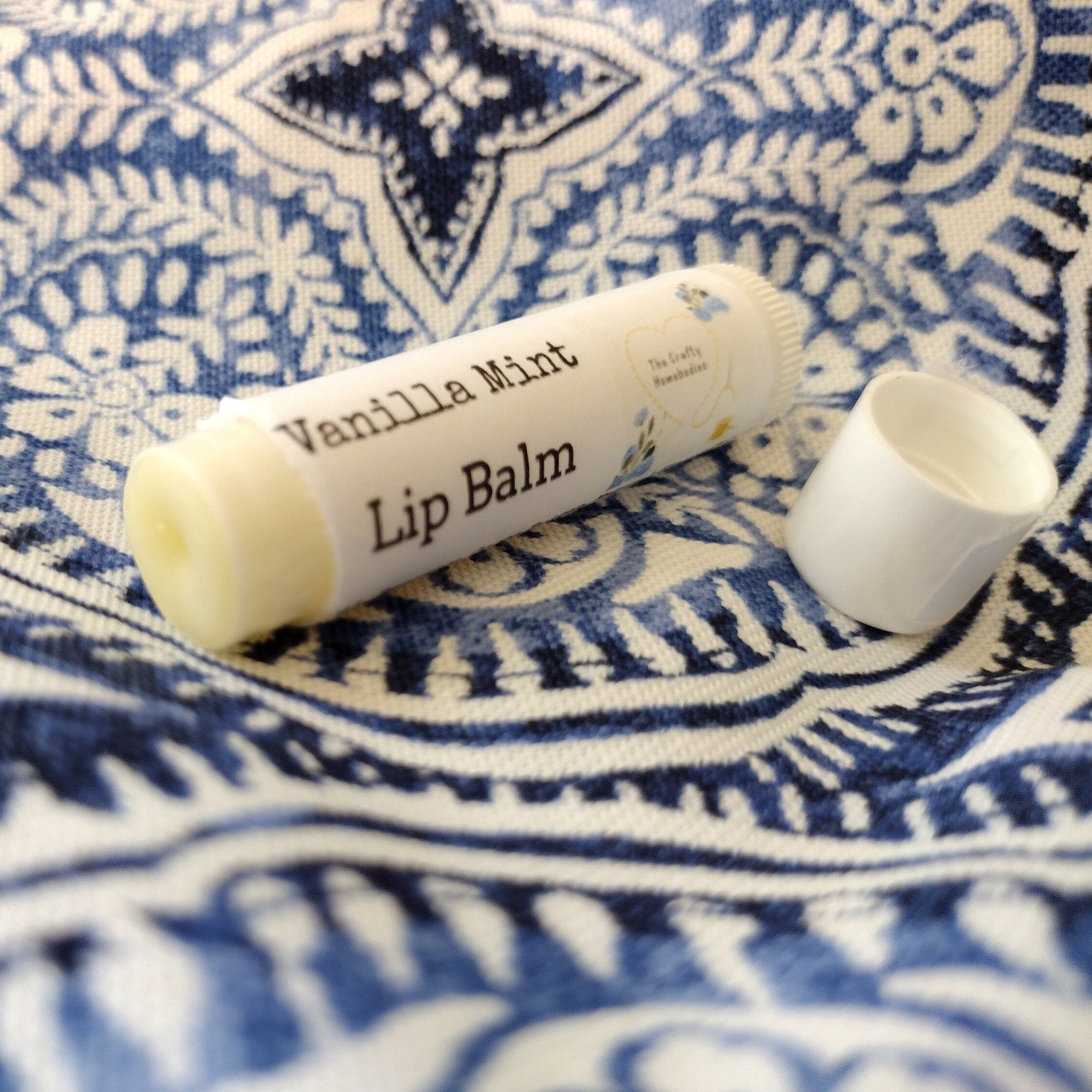 Lip balm tube with white and cream colors, "Vanilla Mint" text, and open cap beside it