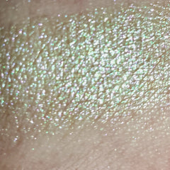 Close-up of fingertips applying shimmery taupe eye shadow to eyelid with soft blending motion
