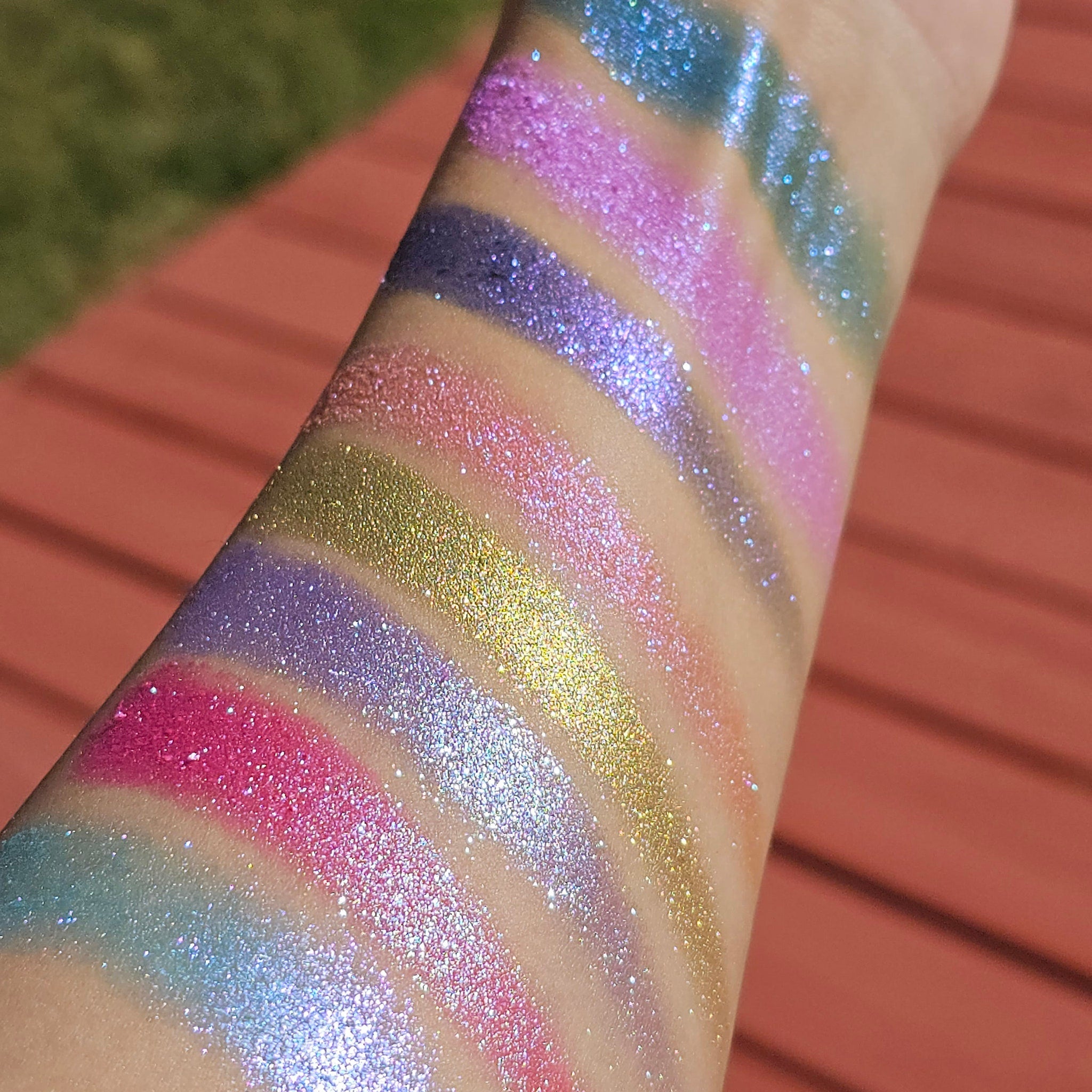 Eyeshadow swatches with various colors, glitter, and applied on arm for color test