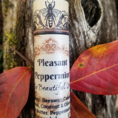Lip balm tube with Pleasant Peppermint text, cream paper, bee graphic, and red leaves in background