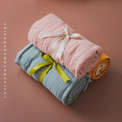 Muslin blankets, pink, blue, and yellow fabric with tied ribbon, "Lauras Handmade Design" text visible