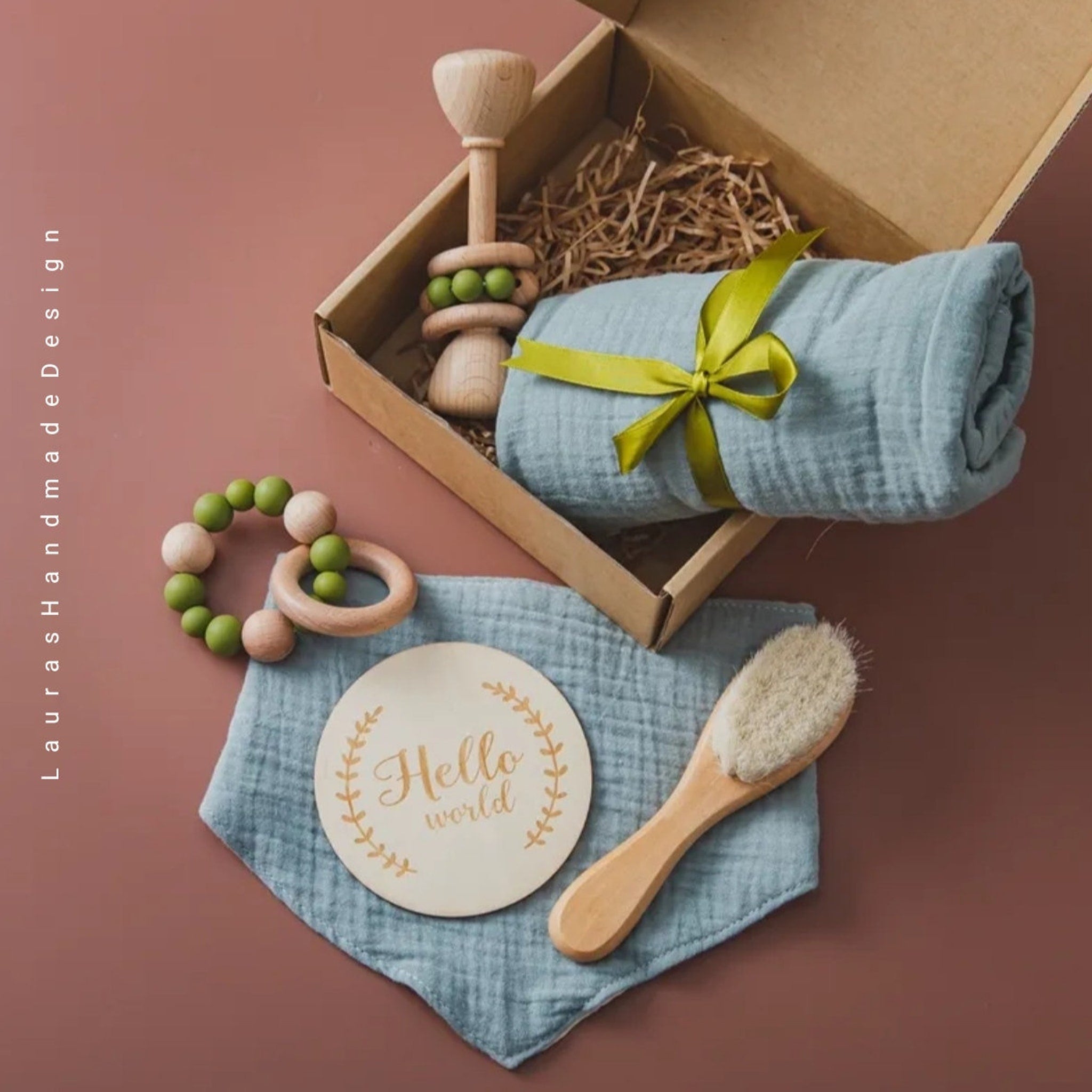 Baby gift set with wooden rattle, blue muslin blanket, and "Hello world" sign