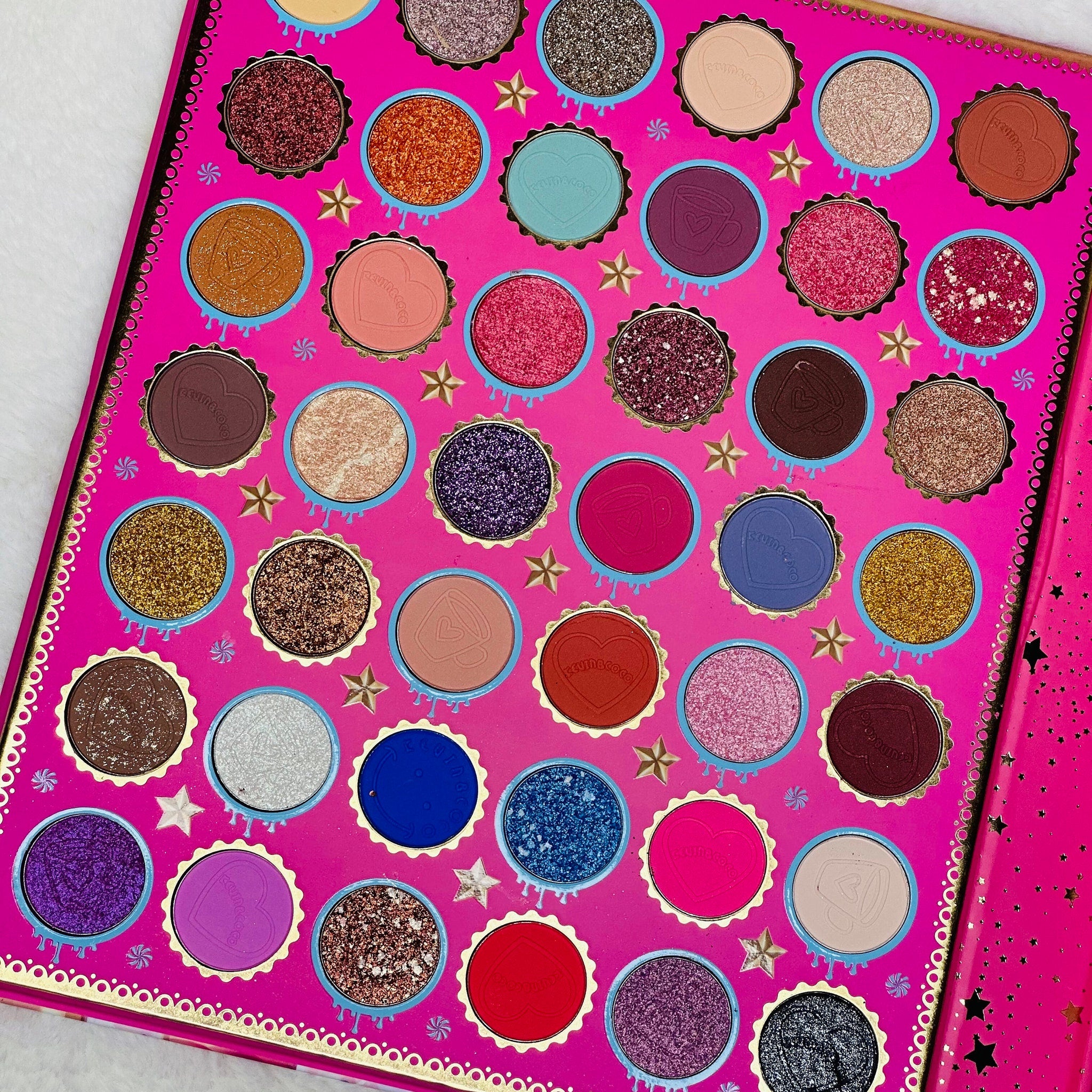 Close-up of pink eye shadow palette with shimmering shades and mirrored compact case