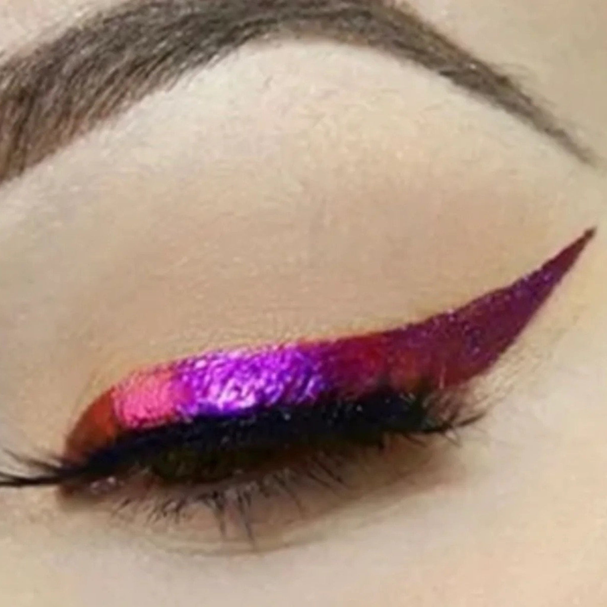 Eyeliner, iridescent purple and red, applied to eyelid for makeup look
