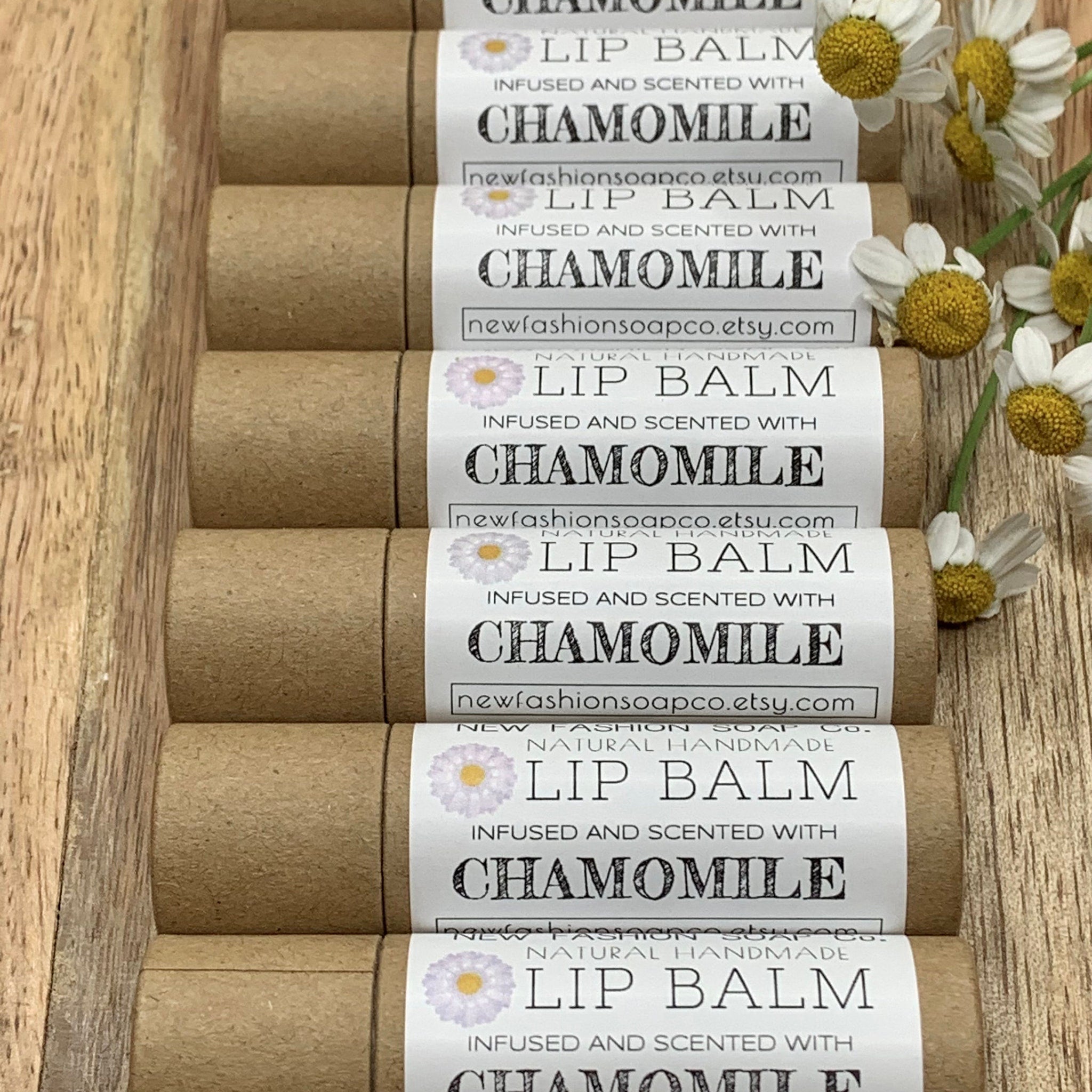 Lip balm tubes with brown paper, white labels, and chamomile flowers, newfashionsoapco.etsy.com text