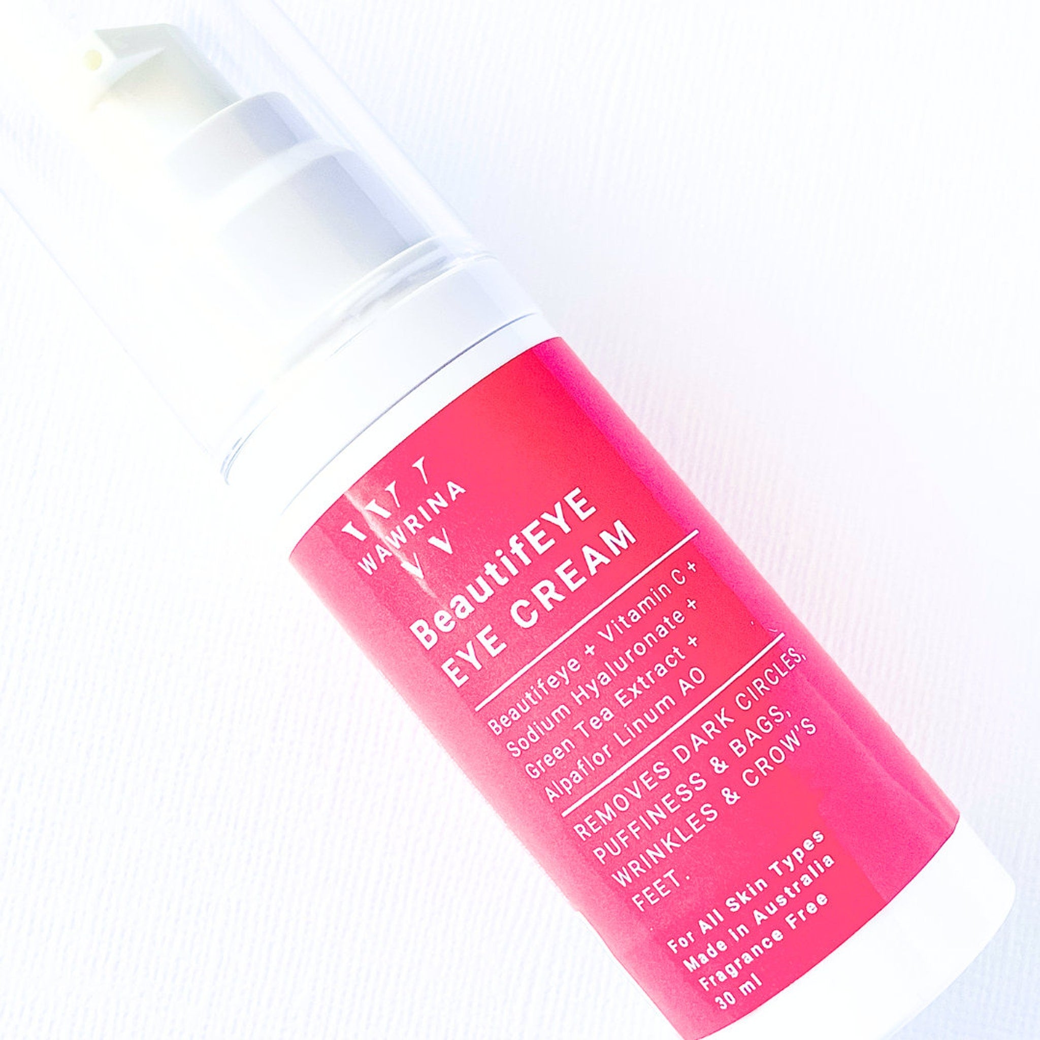 Eye cream bottle with pink and white label, WAWRINA branding, angled on white background