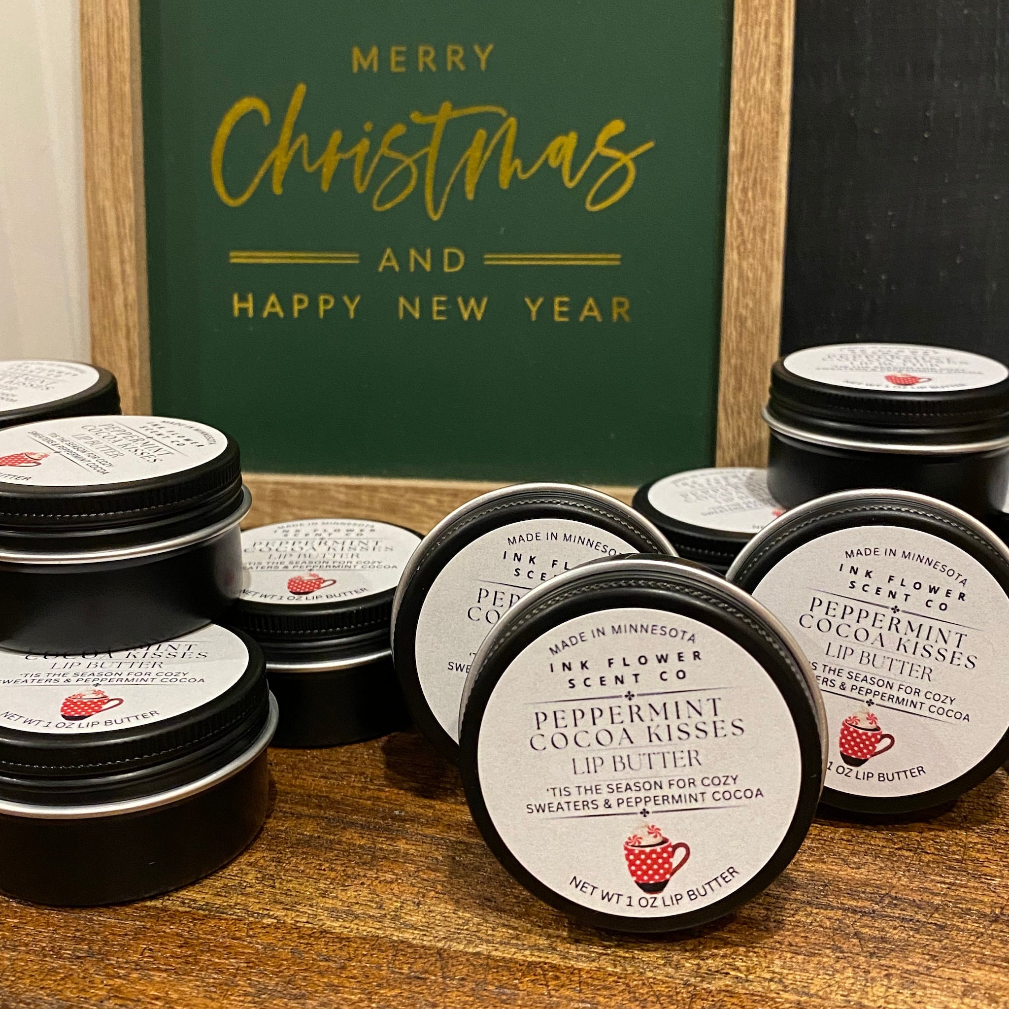 Lip butter tins with black lids, white labels, and red mug graphic, on wooden surface