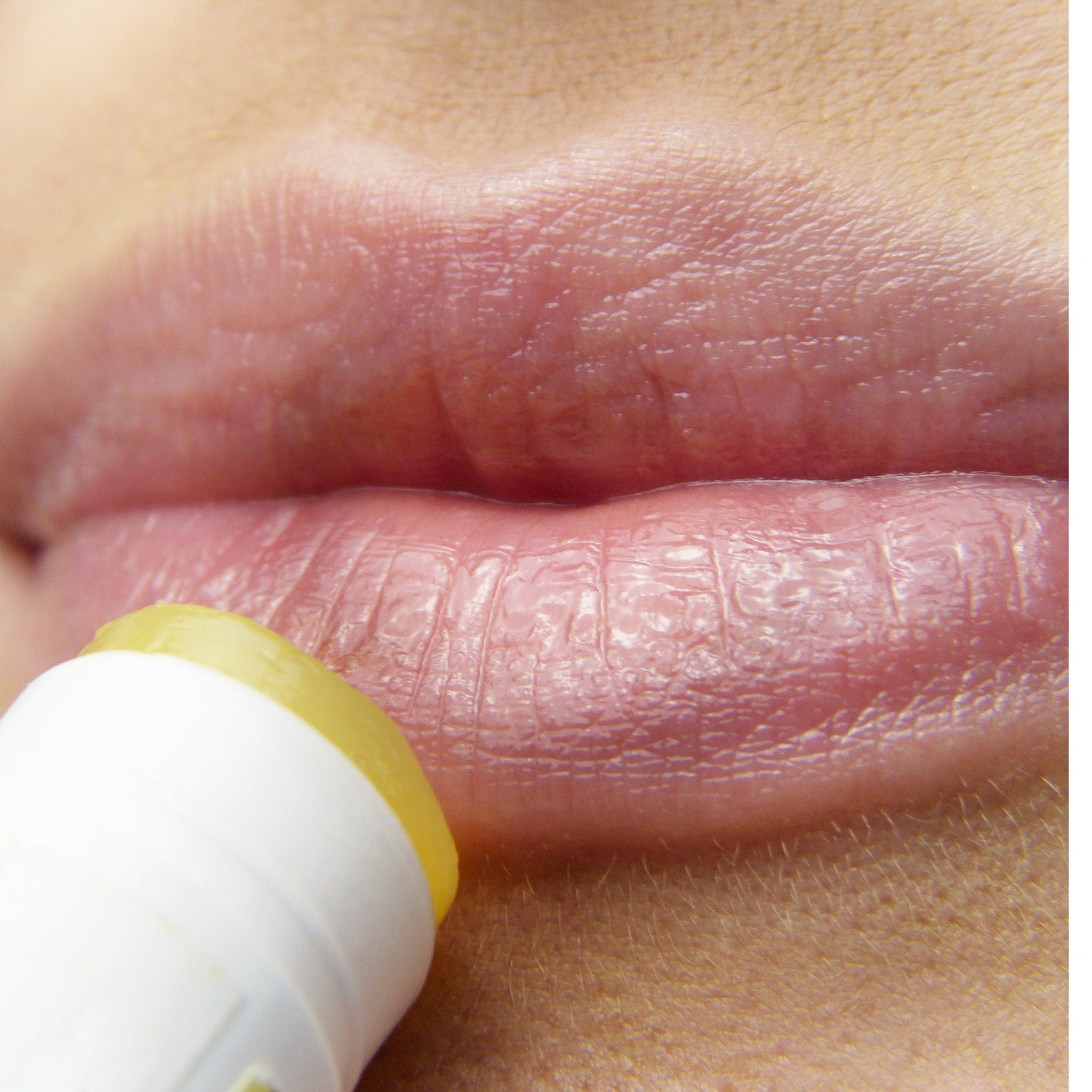 Lip balm application, white and yellow tube, close-up of pink lips