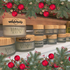Stress relief balm jars with wooden lids, glass jars, and "wildebody" brand text, Christmas decorations