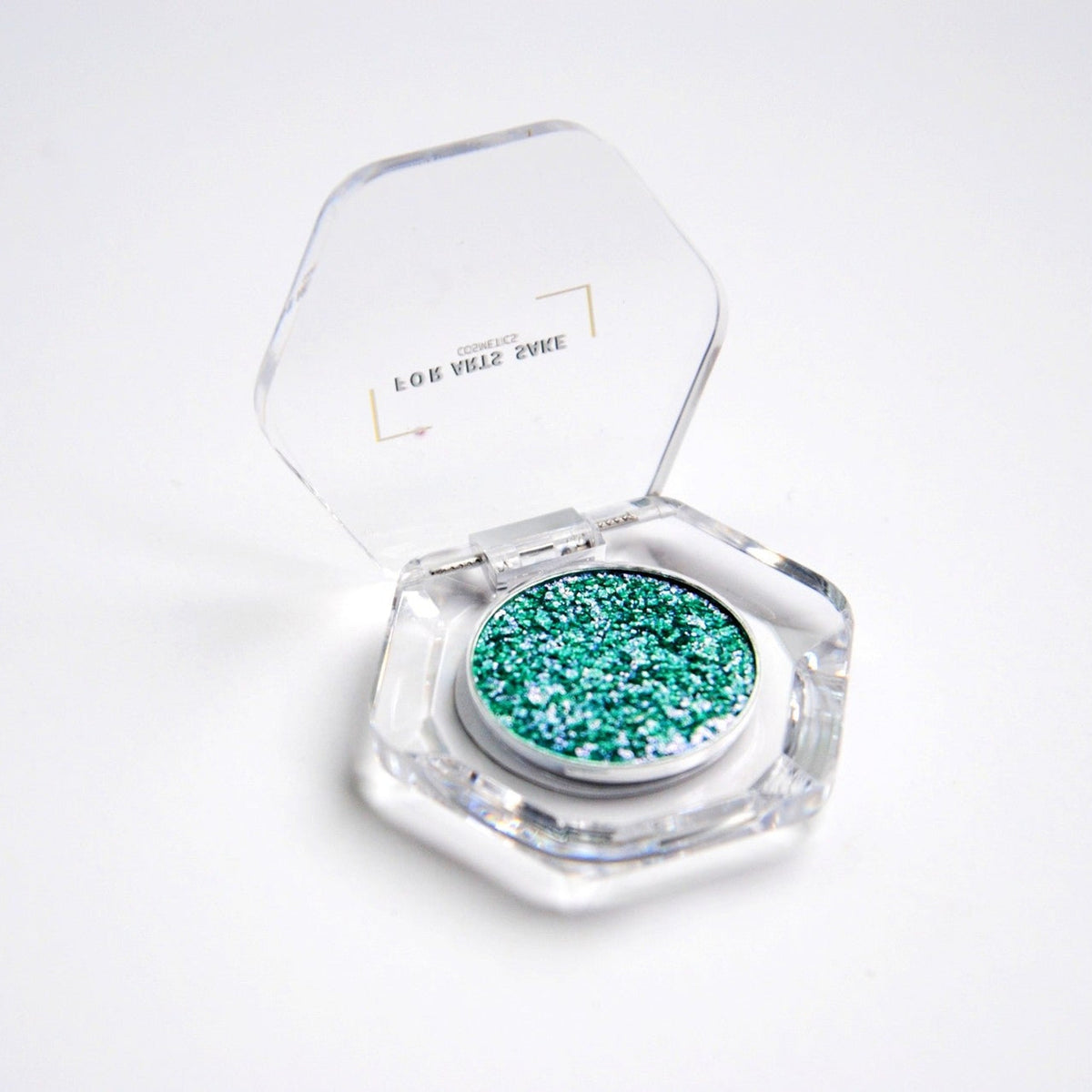 Single eyeshadow pan with teal, blue, and silver iridescent duochrome shift in compact packaging