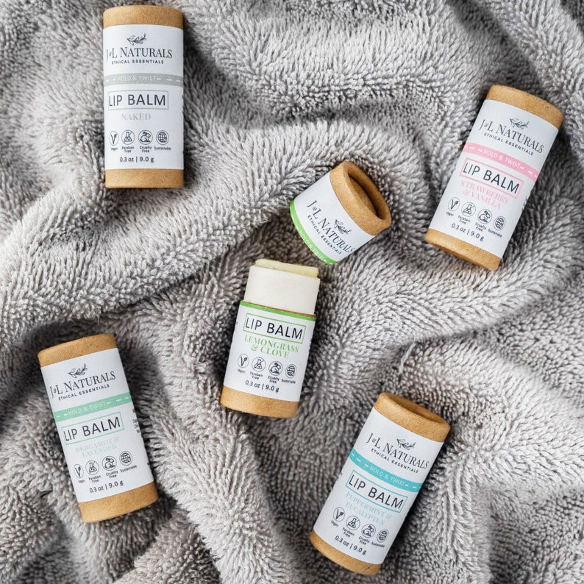 Lip balm tubes with white labels, brown paper tubes, on gray fabric