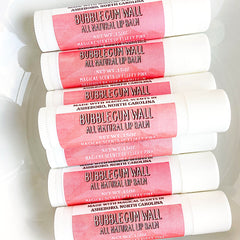 Lip balm tubes with white and pink labels, stacked, Bubblegum Wall brand visible