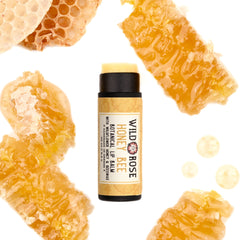 Lip balm tube with black cap, Wild Rose Honey Bee label, surrounded by honeycomb and droplets