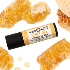 Lip balm with black tube, Wild Rose Honey Bee label, and honeycomb pieces on white background