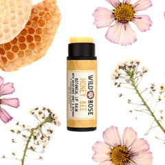Lip balm tube with black cap and yellow label, surrounded by flowers and honeycomb, Wild Rose brand