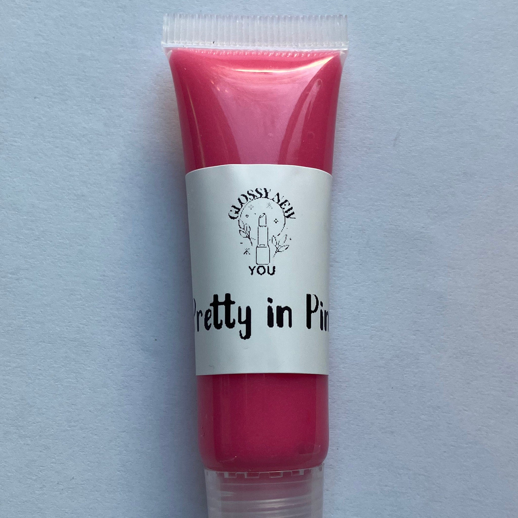 Lip gloss tube with pink gloss, white label, and "Pretty in Pink" text by Glossy New You