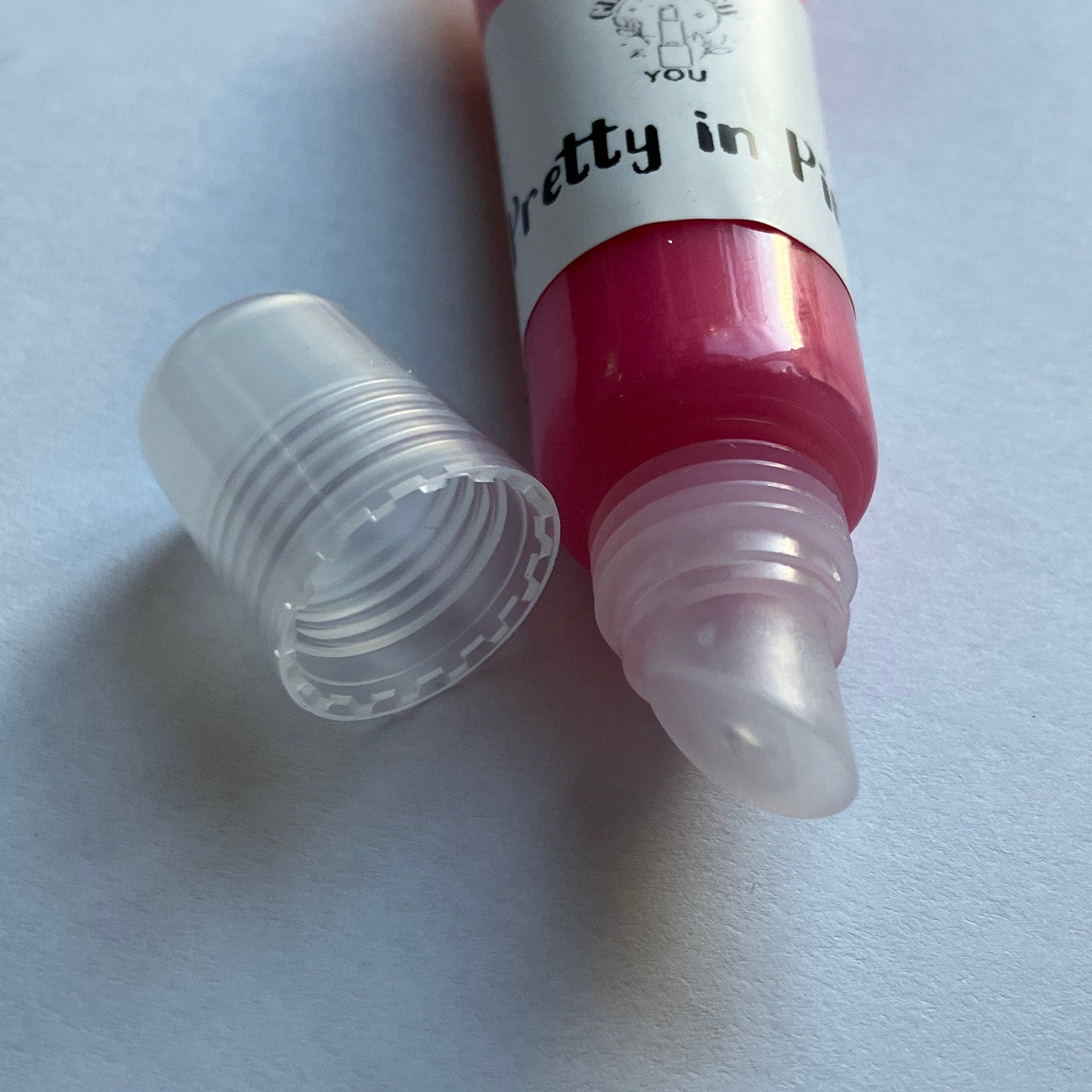 Lip gloss tube with pink gloss, clear plastic tube and cap, "Pretty in Pink" label
