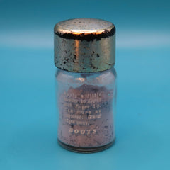 Vintage powder bottle with metal lid, clear glass, and pink powder, Boots brand visible