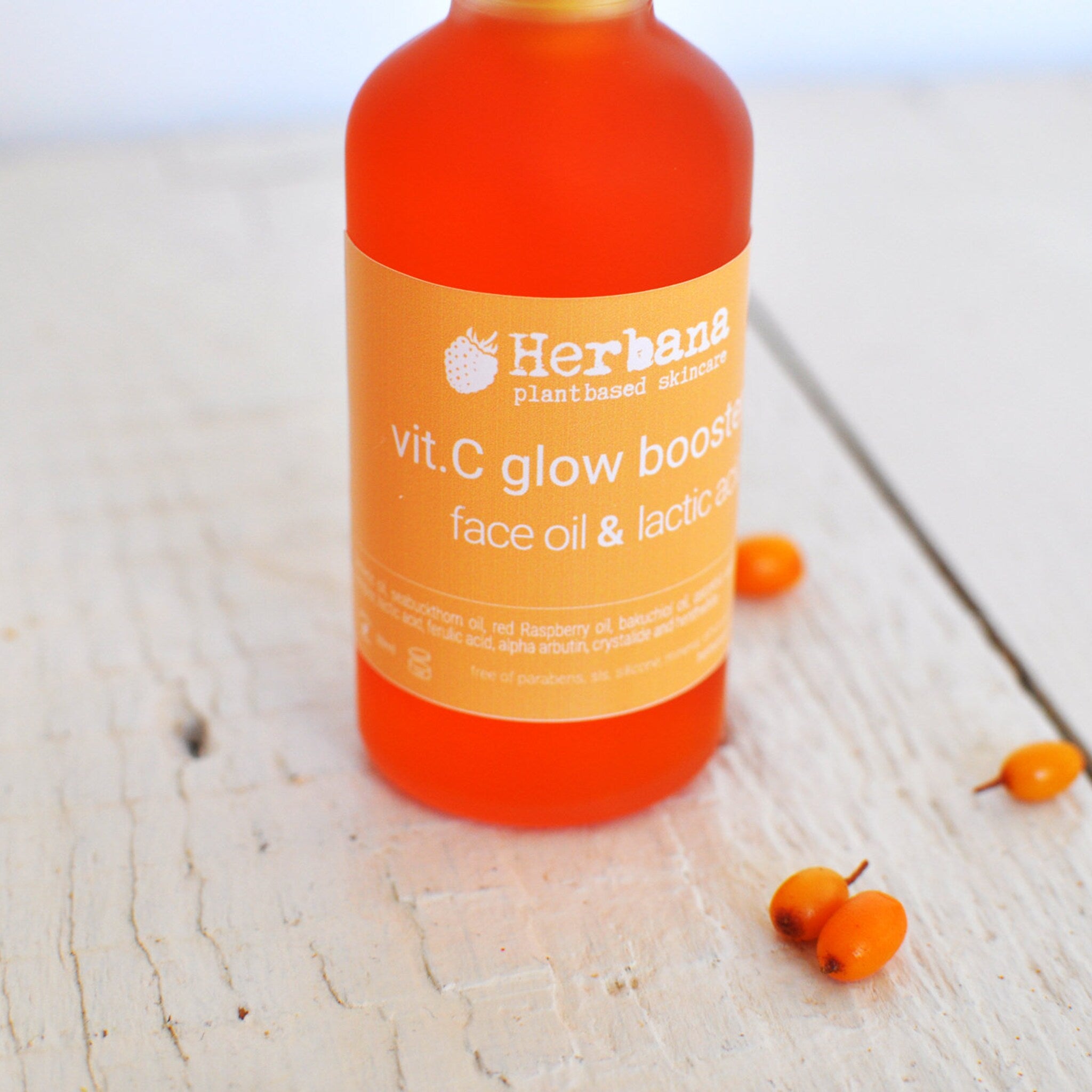 Close-up of amber glass dropper bottle showing golden vitamin C serum with lactic acid, minimal label design