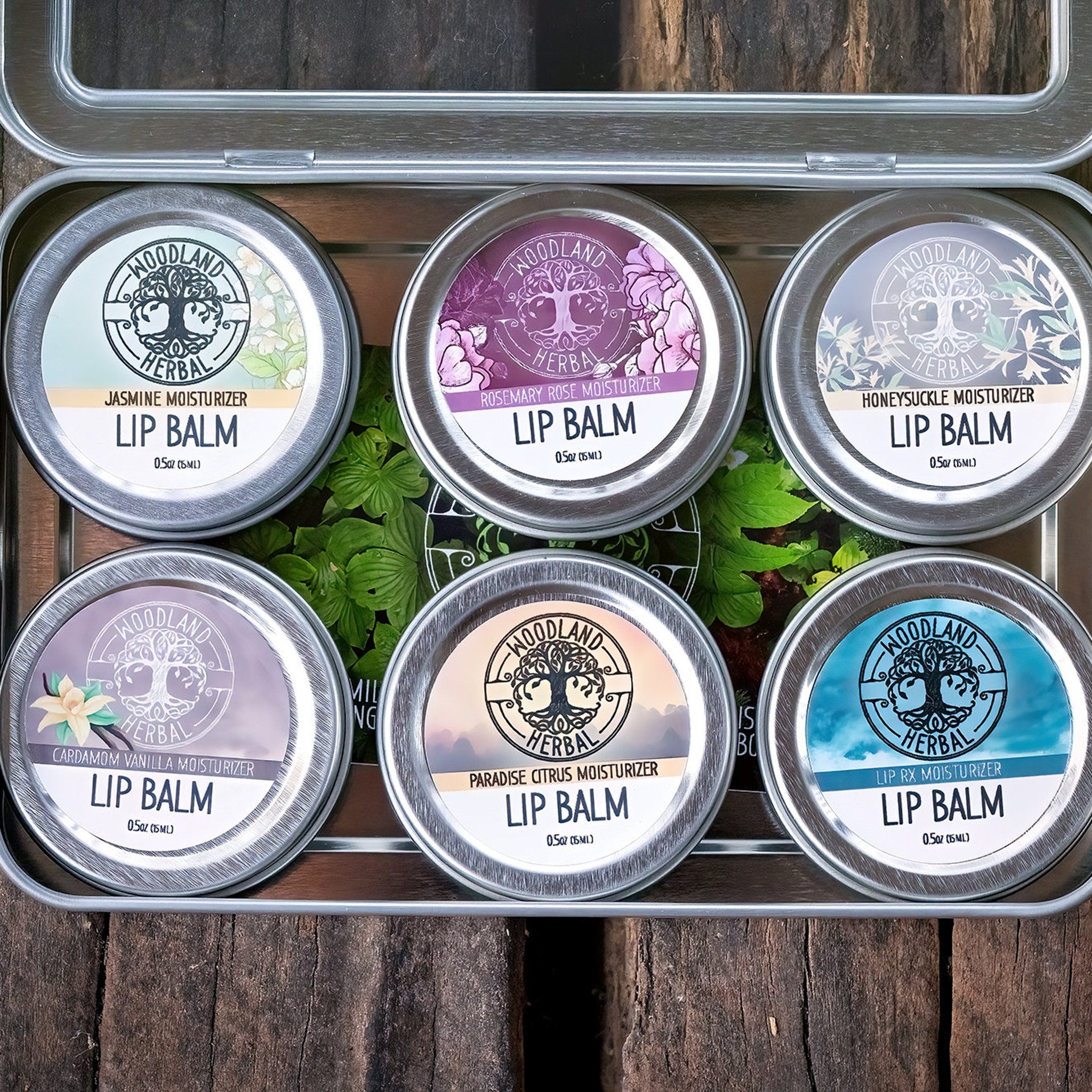 Lip balm tins, silver metal, with Woodland Herbal branding and various colored labels