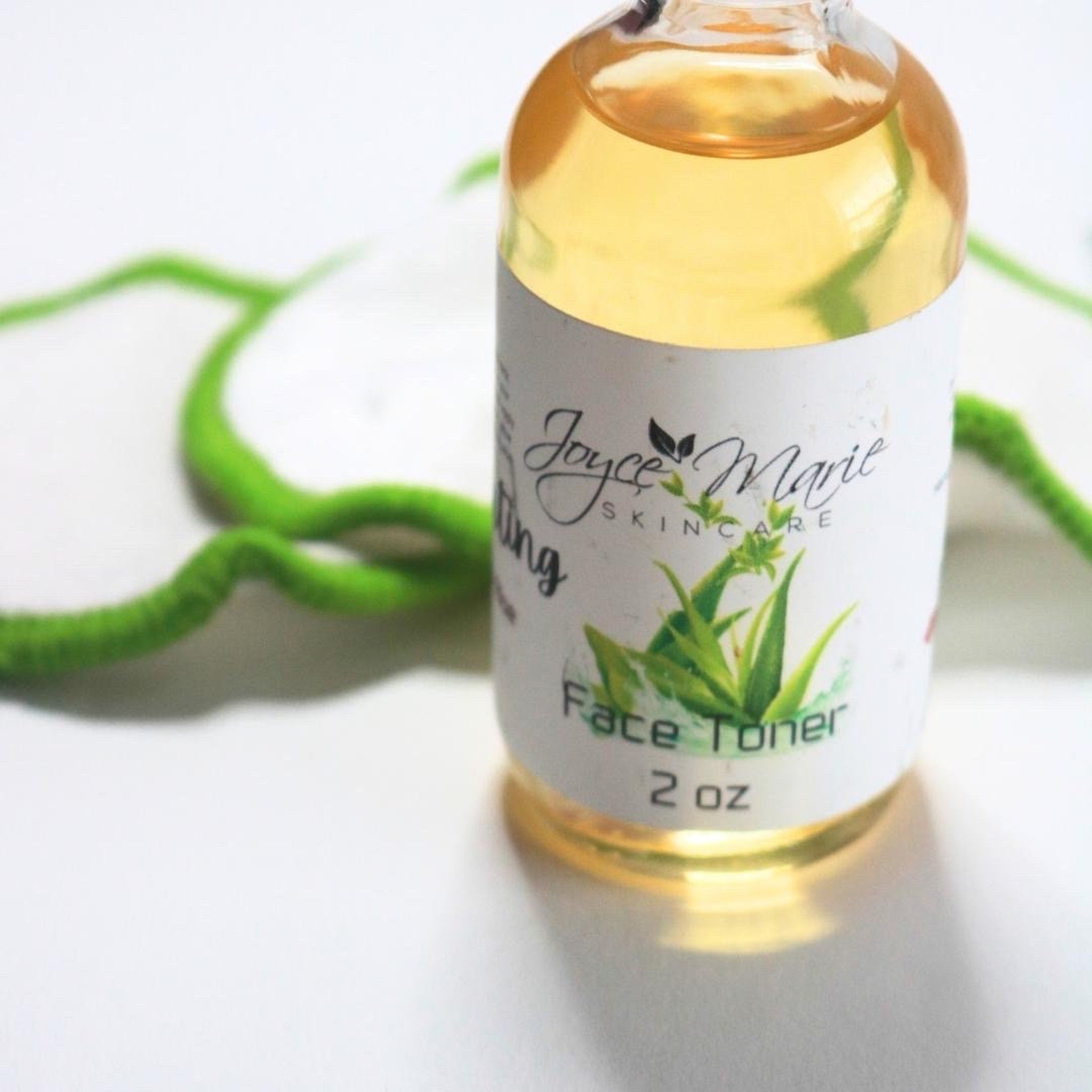 Face toner bottle with yellow liquid, white label, and green accents near green decor