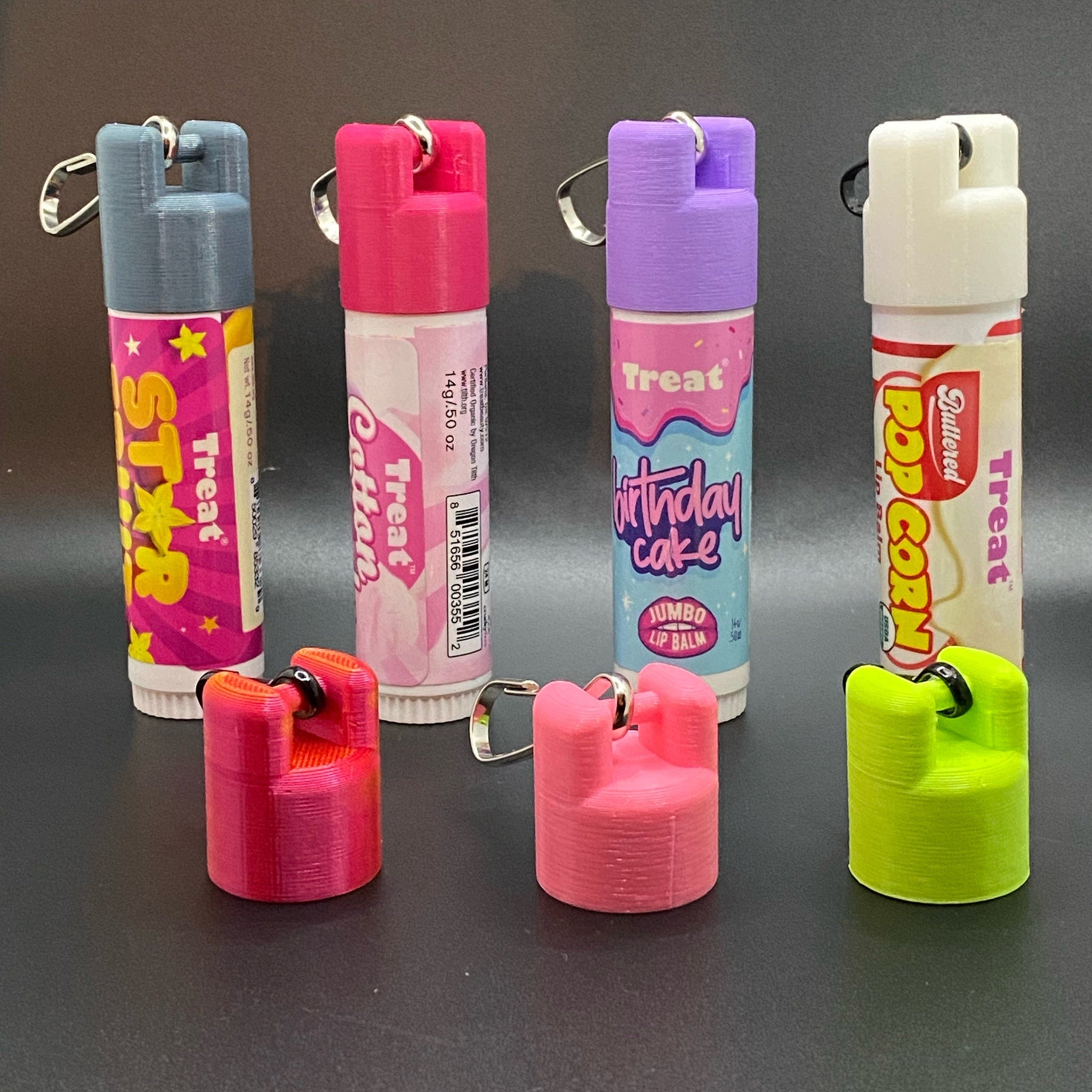 Lip balm tubes with various colors, Treat branding, and 3D-printed keychains attached