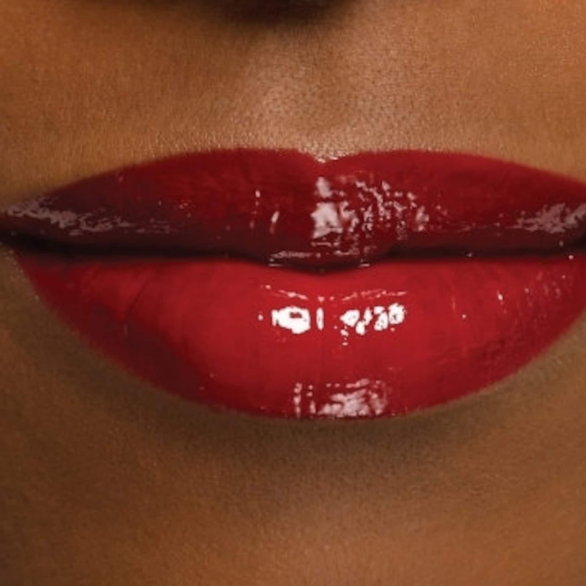 Lip gloss with glossy red finish and dark lip stain, shown on lips