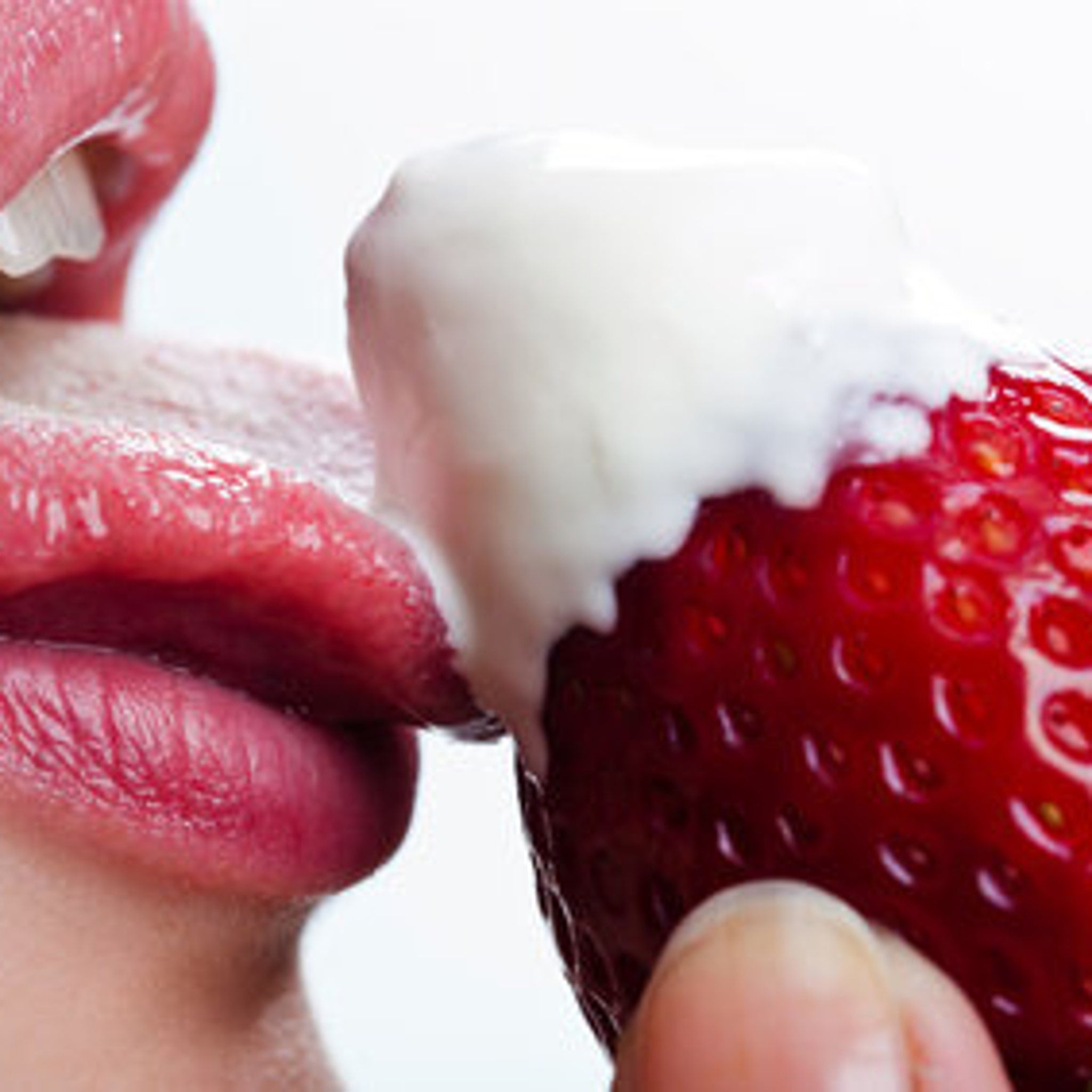 Strawberry with white cream, red fruit, close up of mouth and hand holding it