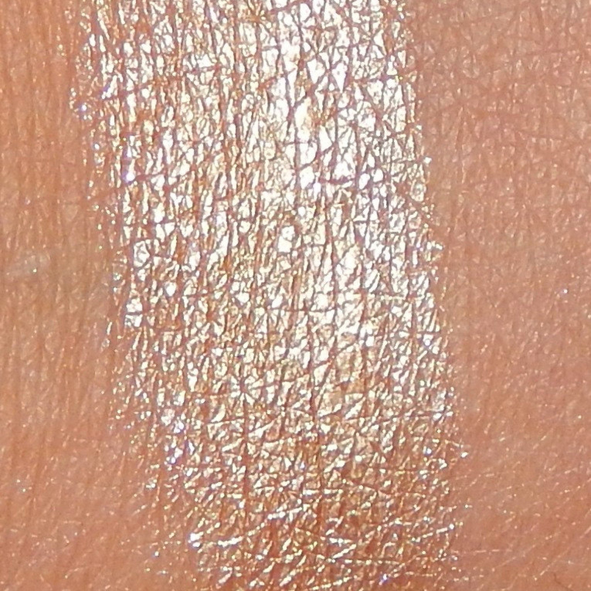Woman applying shimmering bronze eyeshadow from trio palette with fingertip, blending along eyelid crease