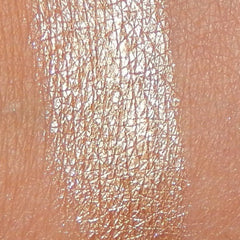Woman applying shimmering bronze eyeshadow from trio palette with fingertip, blending along eyelid crease
