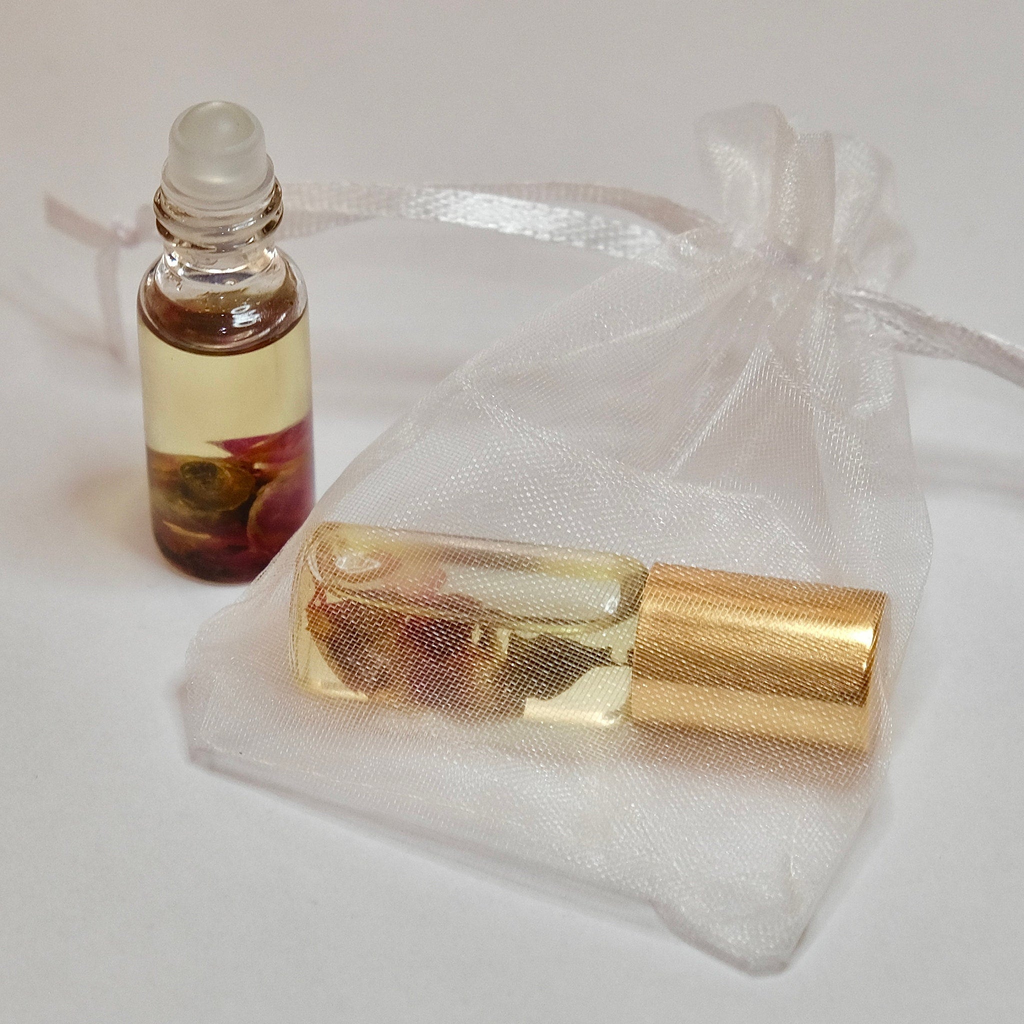 Essential oil bottles with clear glass, gold cap, and white organza bag