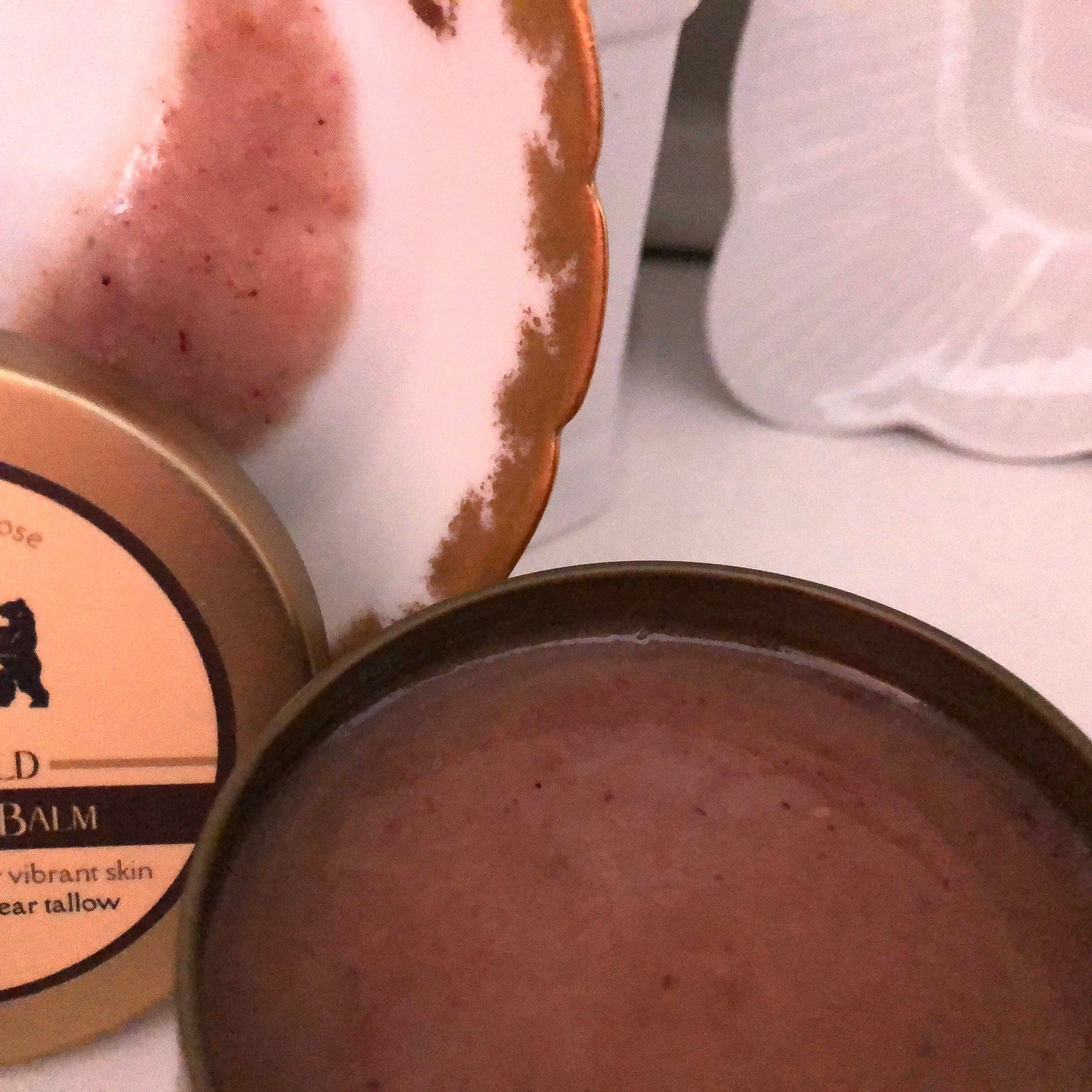 Balm with brown color and round metal container, next to a decorative plate