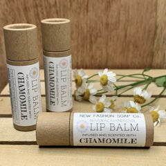 Lip balm tubes in brown cardboard with white label, NEW FASHION SOAP Co. branding, and chamomile flowers