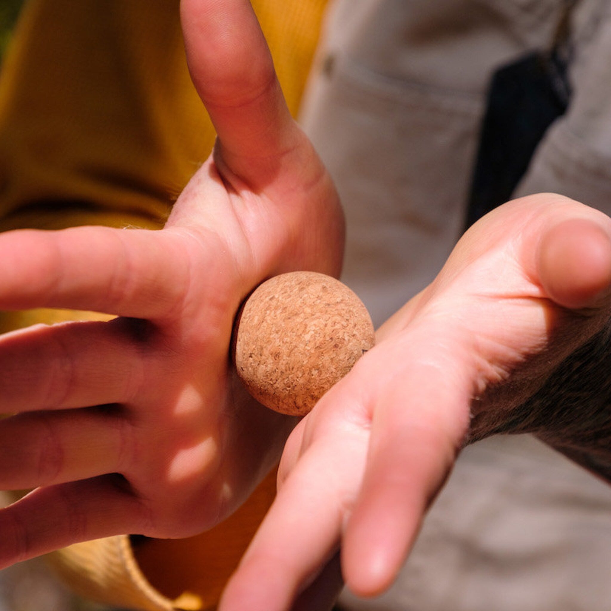 Cork ball held in hands, brown cork material, close-up view of hands and ball