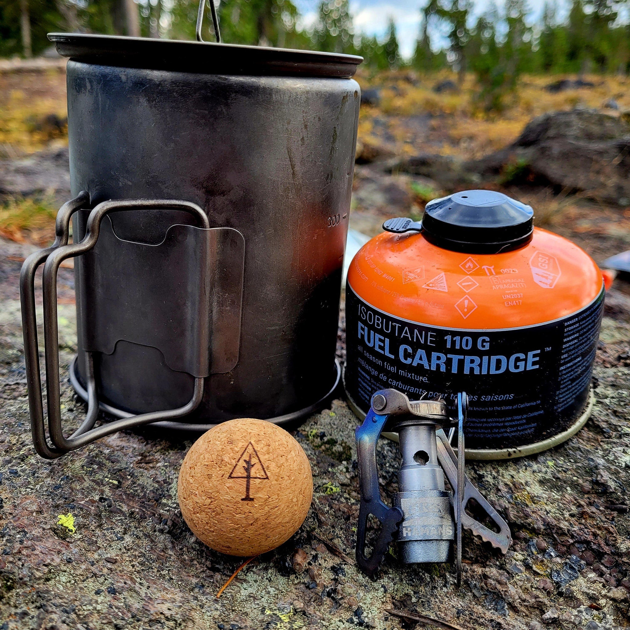 Camping stove and fuel canister with black and orange colors, metal construction, and text visible
