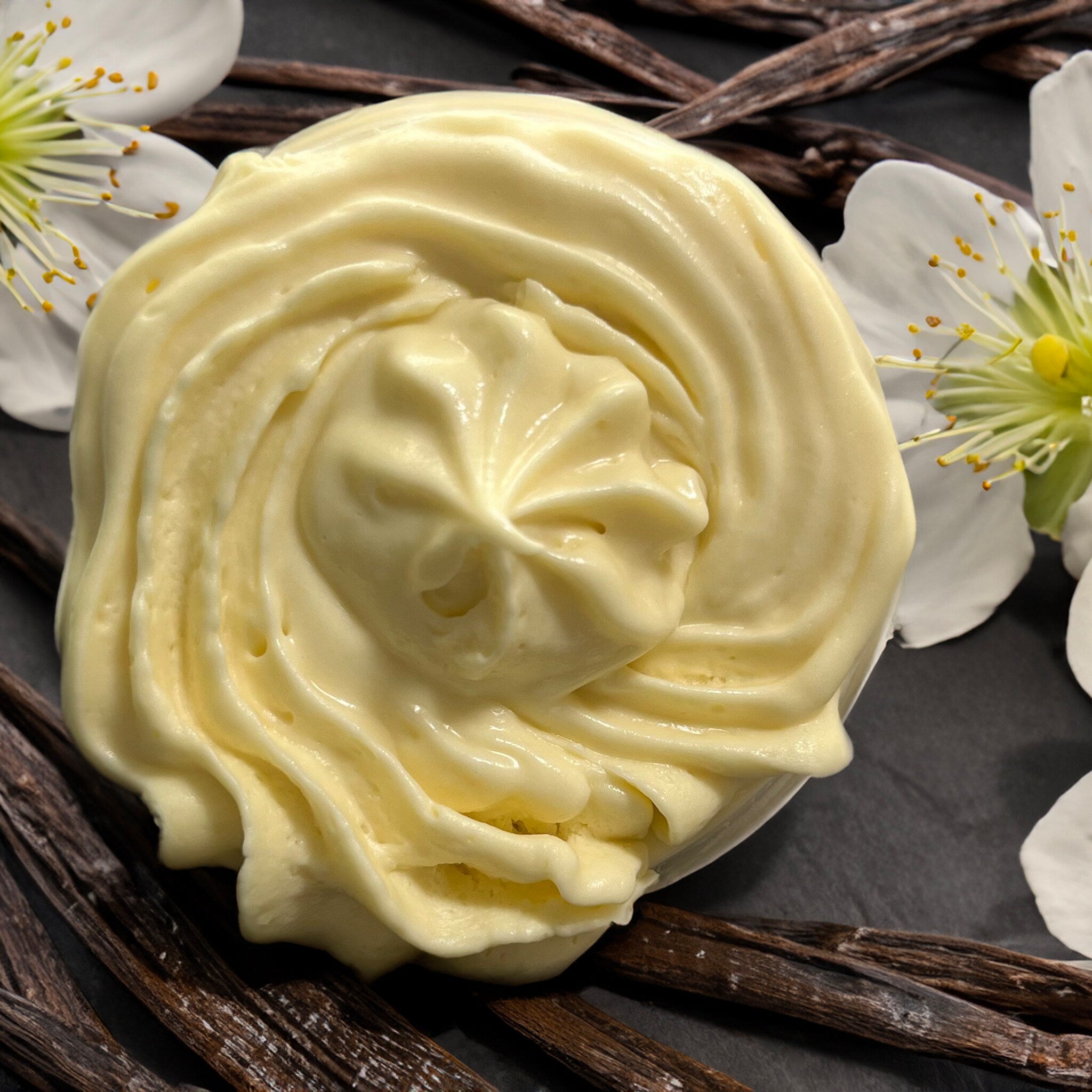 Close-up of creamy vanilla bean body butter with whipped texture in a white jar, showcasing rich consistency