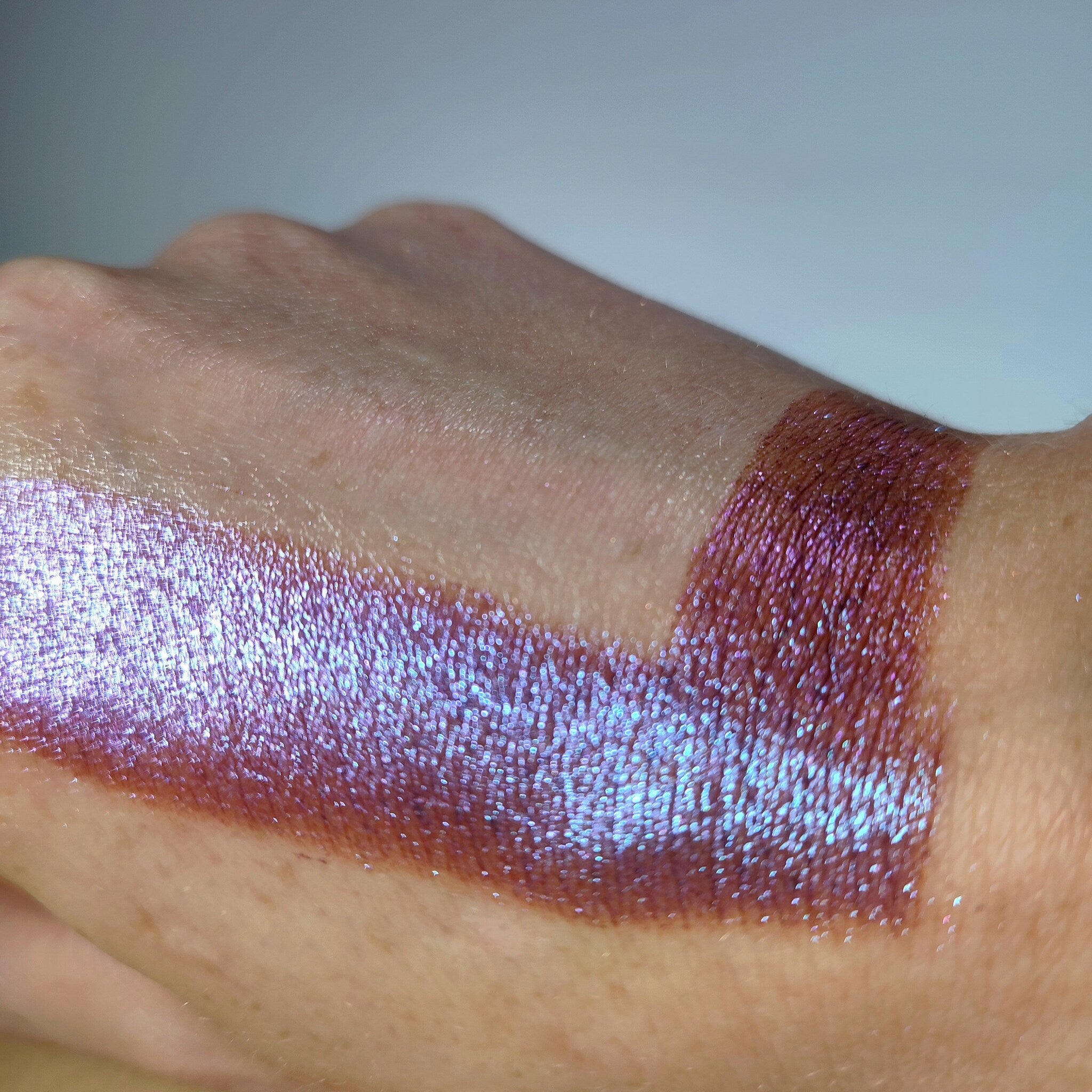 Close-up of fingertips applying shimmery taupe eye shadow to eyelid with soft blending motion