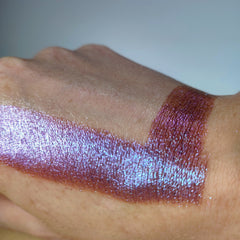 Close-up of fingertips applying shimmery taupe eye shadow to eyelid with soft blending motion