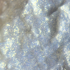 Close-up of sparkling gold liquid eyeshadow with shimmering champagne flecks in sleek tube