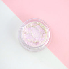 Sparkling blue iridescent liquid eyeshadow in frosted glass bottle with silver cap, shimmering under light